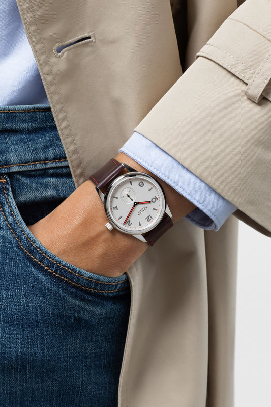 NOMOS Club 38 on the wrist with a beige coat. Image: NOMOS Glashütte.